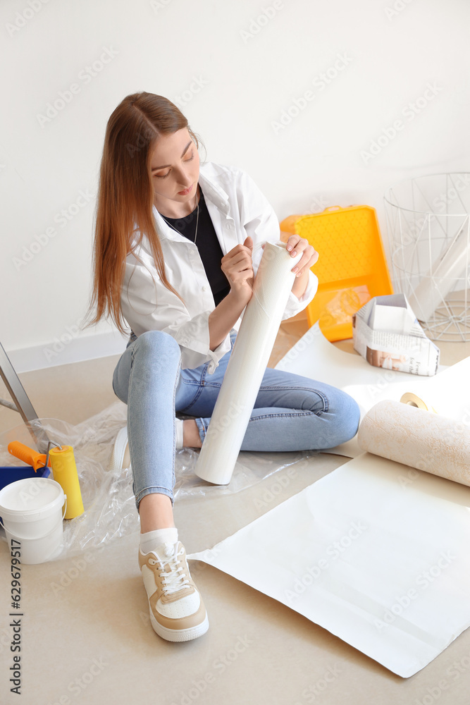 Young woman with wallpaper roll in room