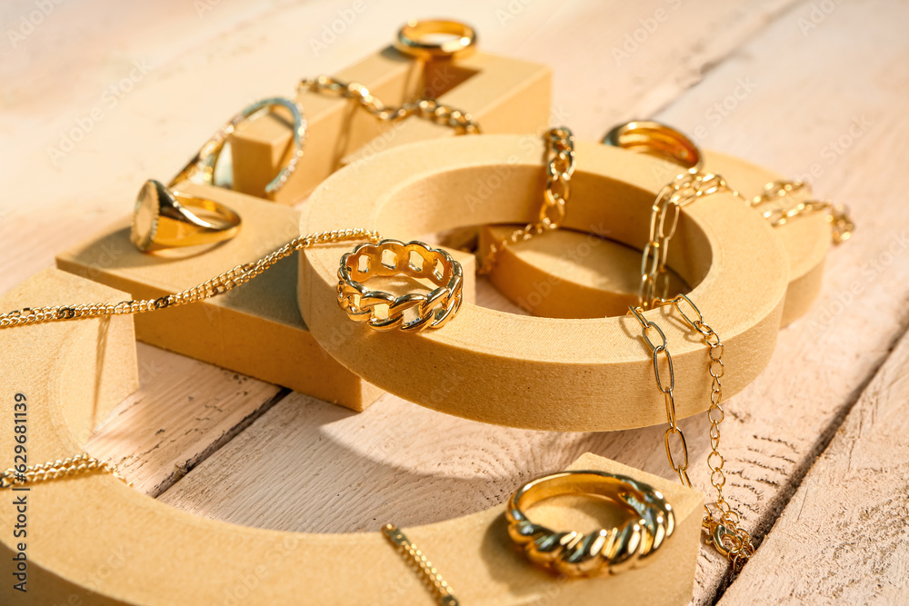 Decorative podiums with golden jewellery on wooden background