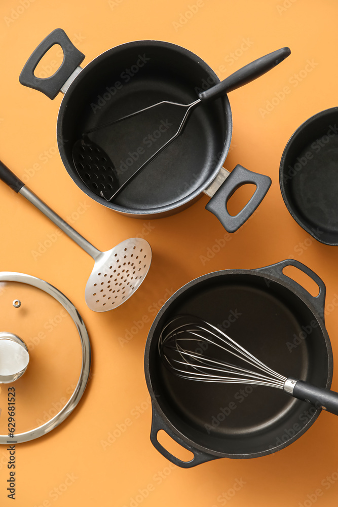 Set of different kitchen utensils on orange background