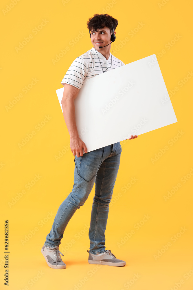 Male technical support agent with blank poster on yellow background