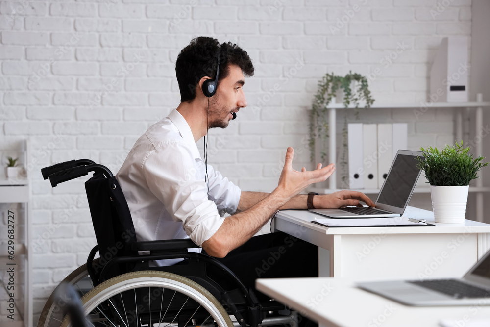 Male technical support agent with physical disability working in office