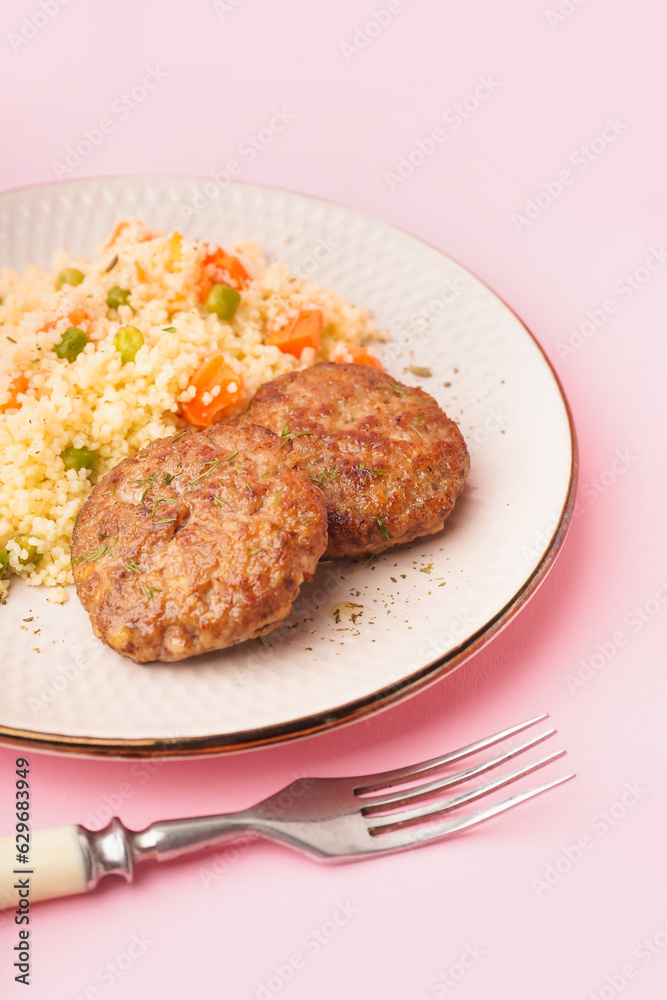 Cutlets with bulgur, boiled vegetables and fork on pink background