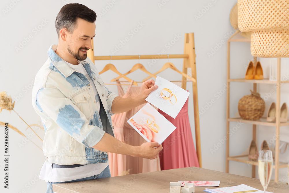 Male wedding planner with pictures of rings in office