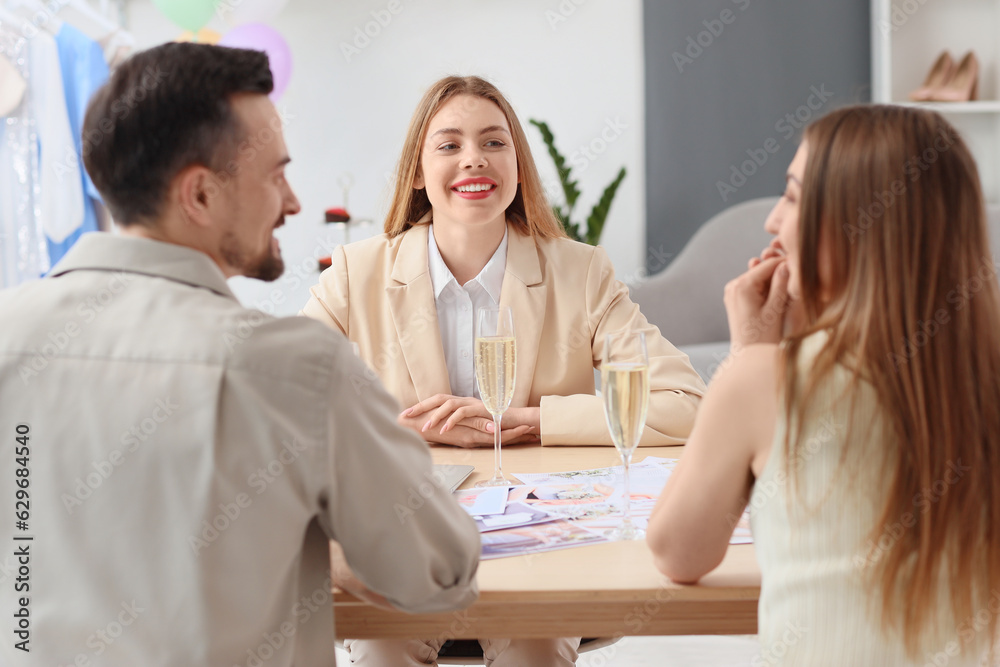 Female wedding planner working with couple in office