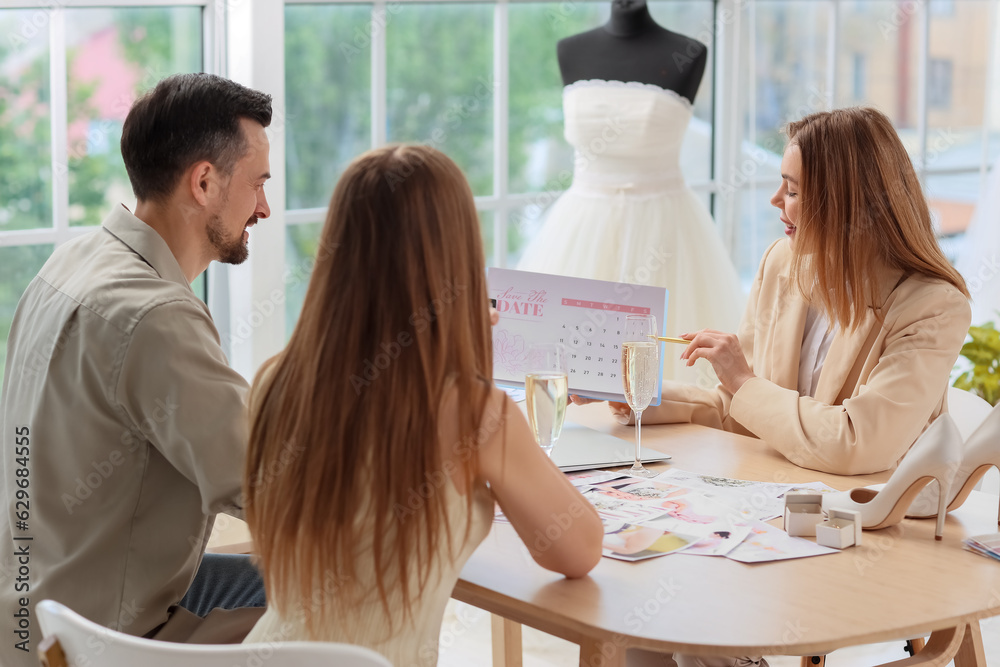 Female wedding planner working with couple in office