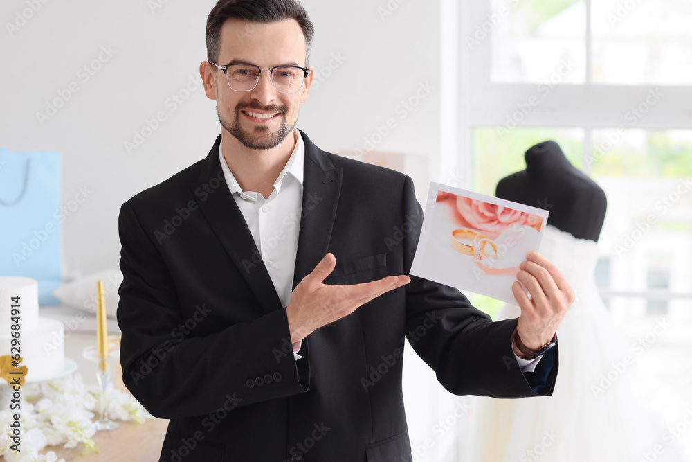 Male wedding planner with picture of rings in office