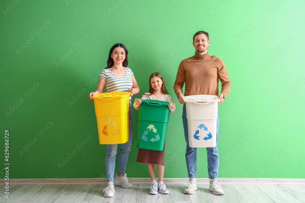 Family with recycle bins near green wall