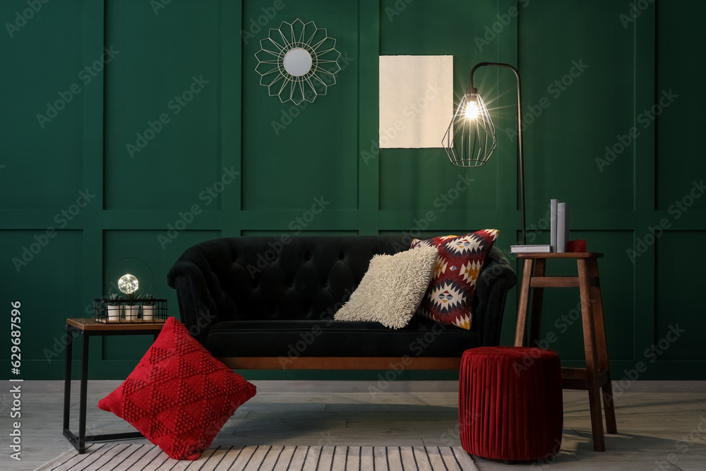 Interior of living room with green sofa, coffee table and glowing lamp