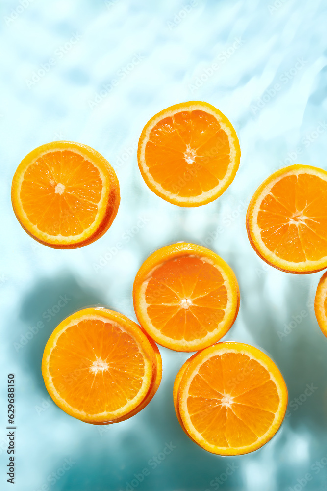 Slices of fresh orange in water on blue background