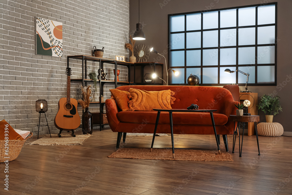 Interior of dark living room with glowing lamps, sofa and tables