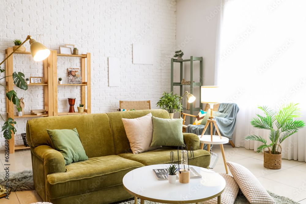 Interior of living room with glowing lamps, sofa and houseplants