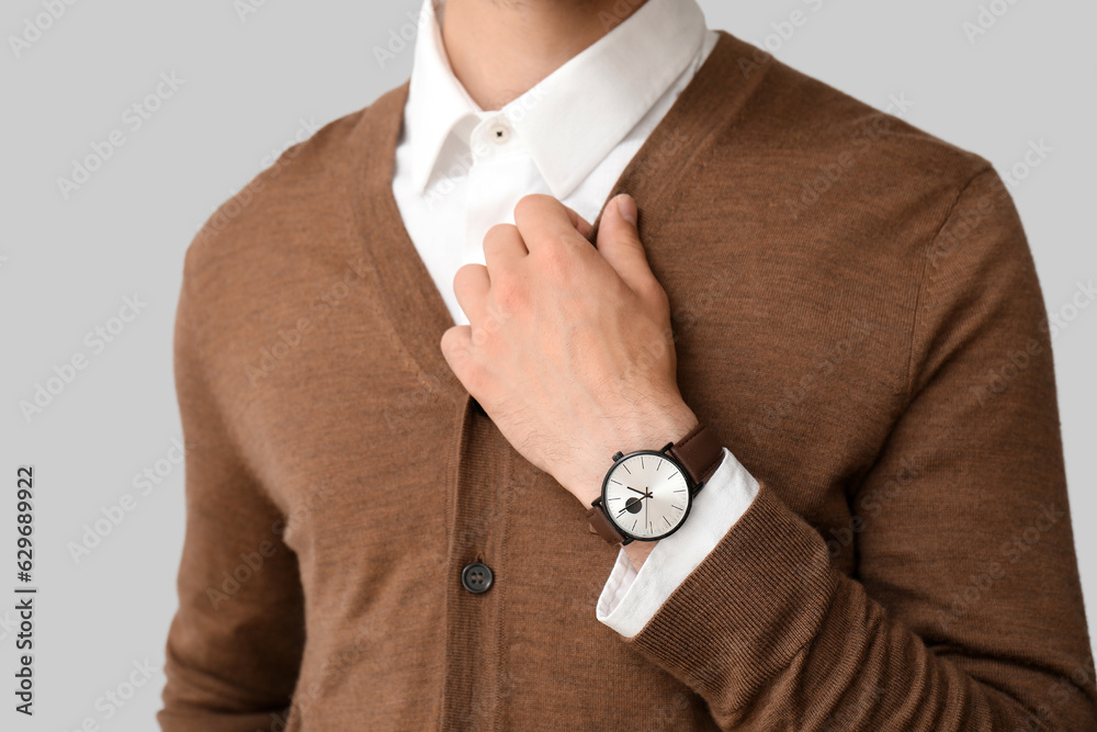 Stylish young man with wristwatch on grey background