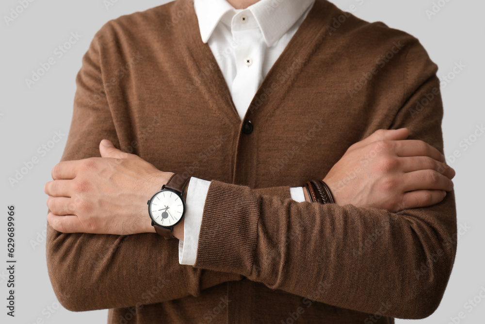 Stylish young man with wristwatch on grey background