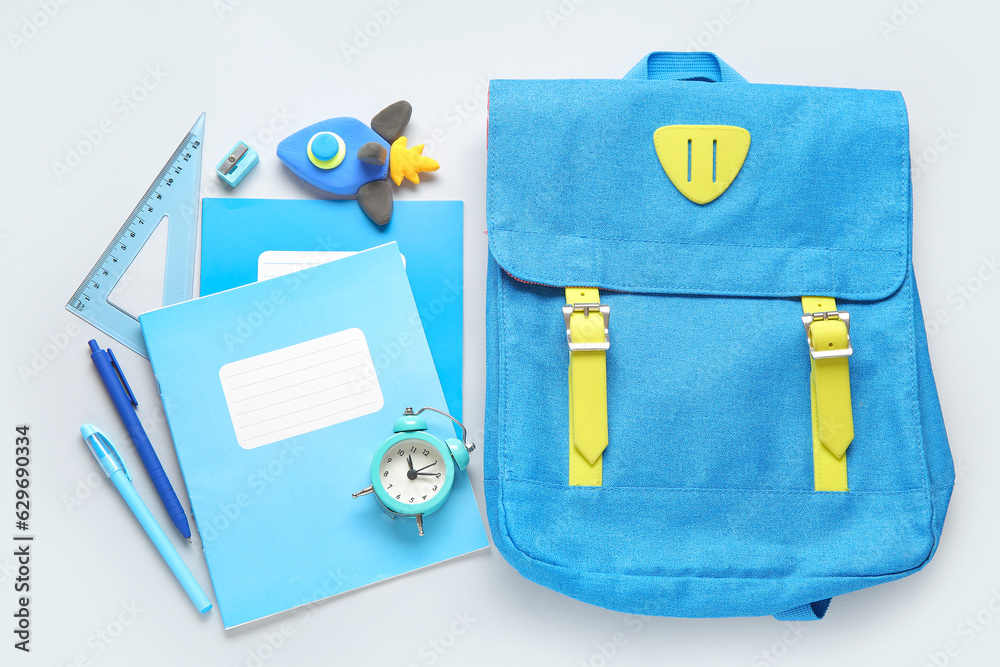 Backpack with rocket made of plasticine, alarm clock and stationery on grey background