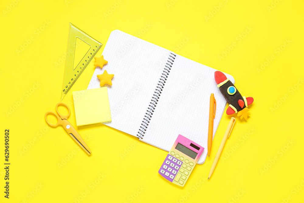 Blank notebook with rocket made of plasticine and stationery on yellow background