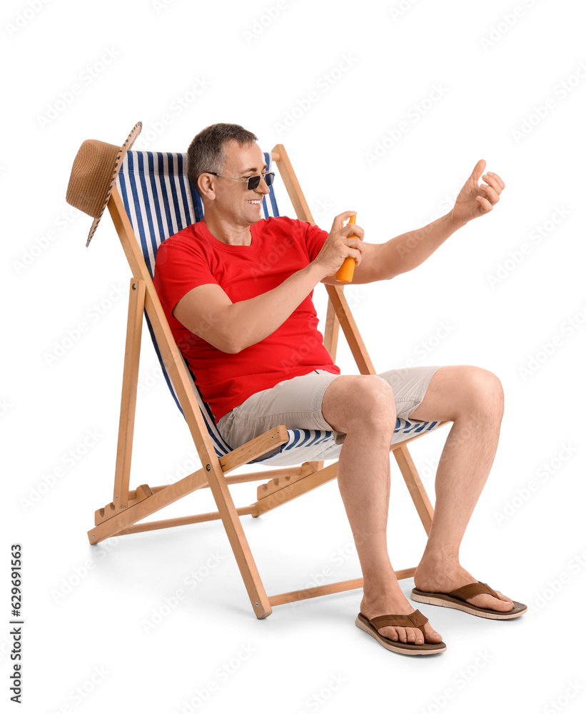 Mature man applying sunscreen cream in deck chair on white background