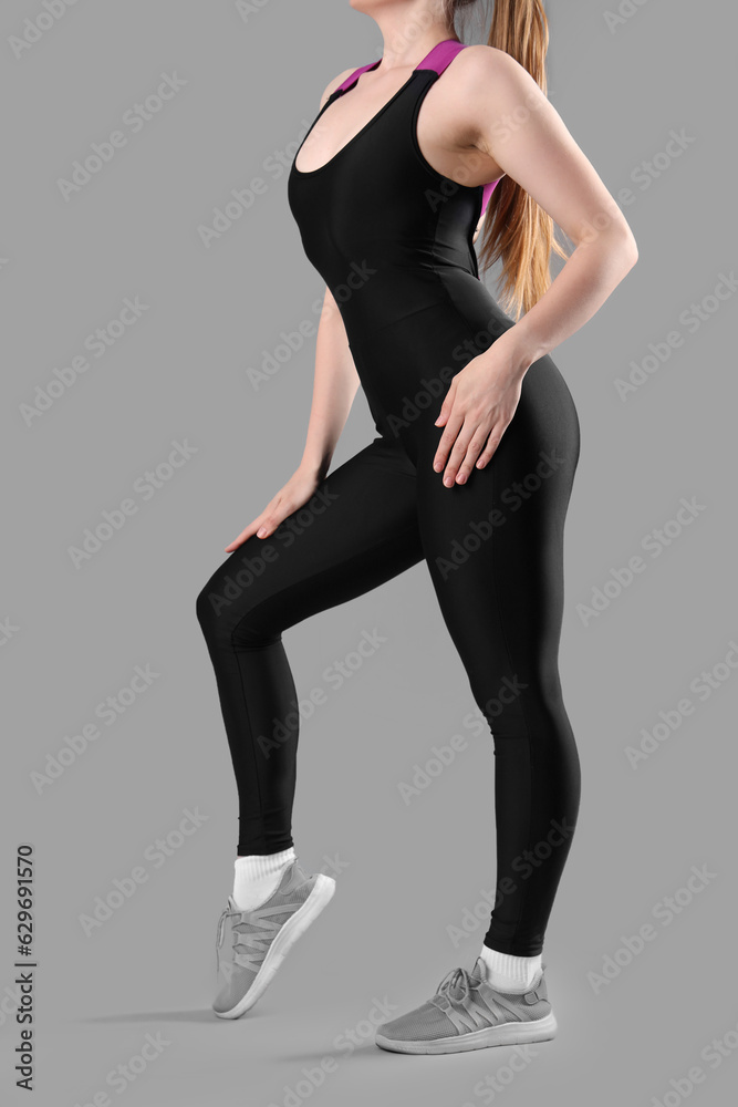 Young woman in sportswear on grey background