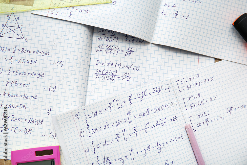 Open copybooks with math formulas as background, closeup