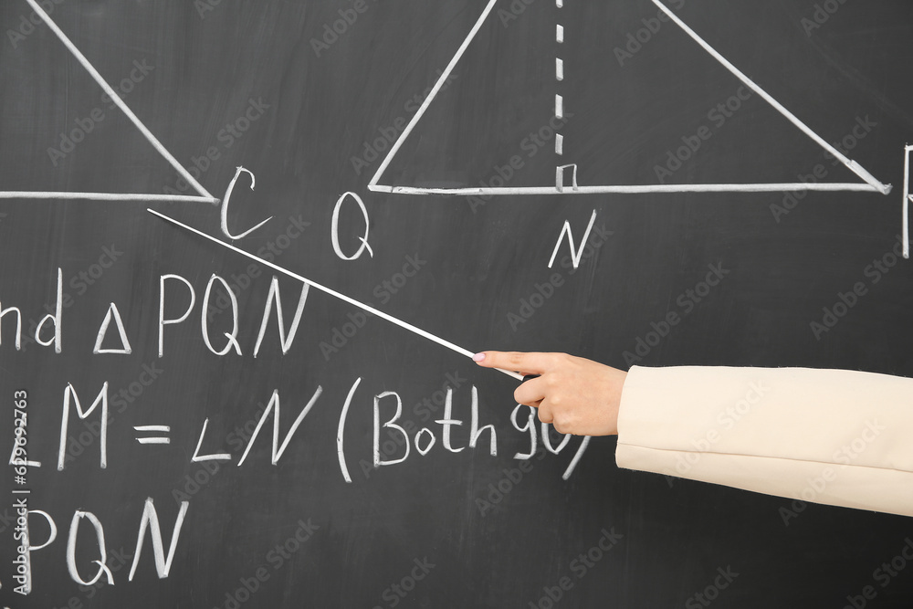 Female teachers hand with pointer explaining math formulas on blackboard