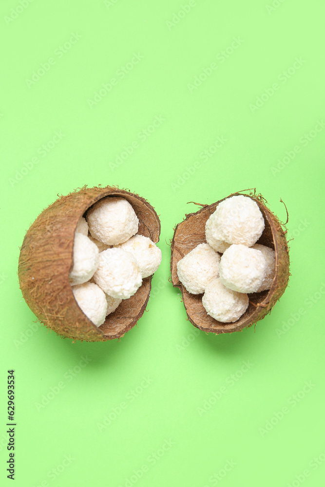 Coconut shells with white chocolate candies on green background