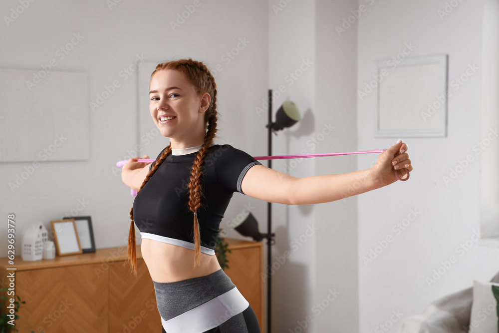 Sporty young woman stretching with rope at home