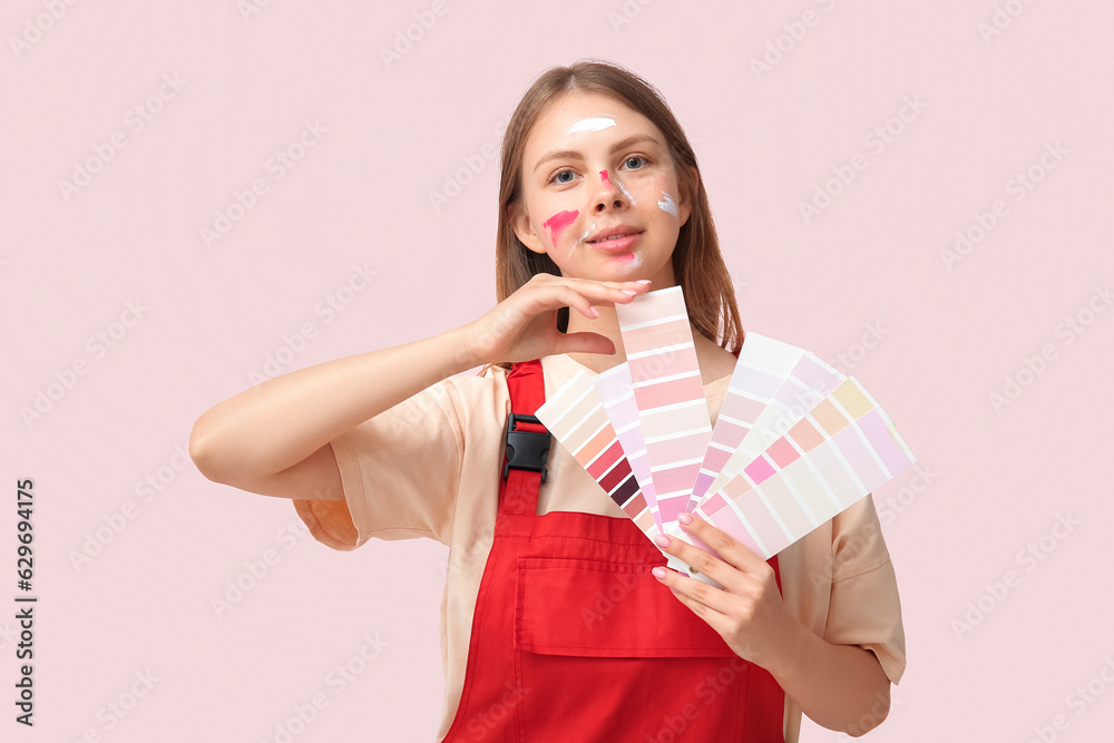 Female decorator with many color samples on pink background