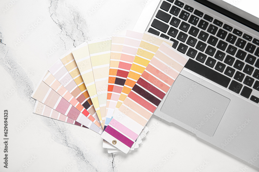 Many color palettes and laptop on light background, top view