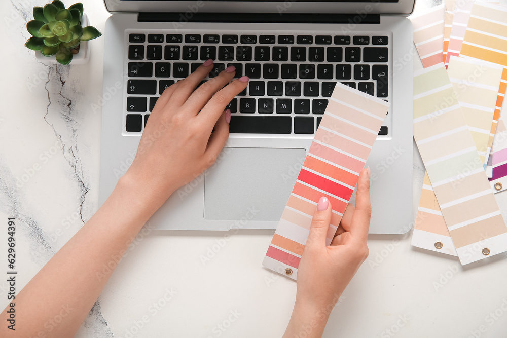 Female hands, color palettes and laptop on light background