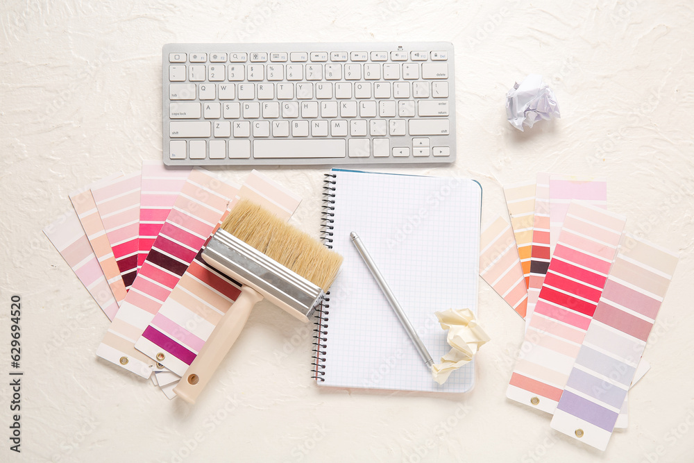 Color palettes, PC keyboard, notebook and brush on light background, top view