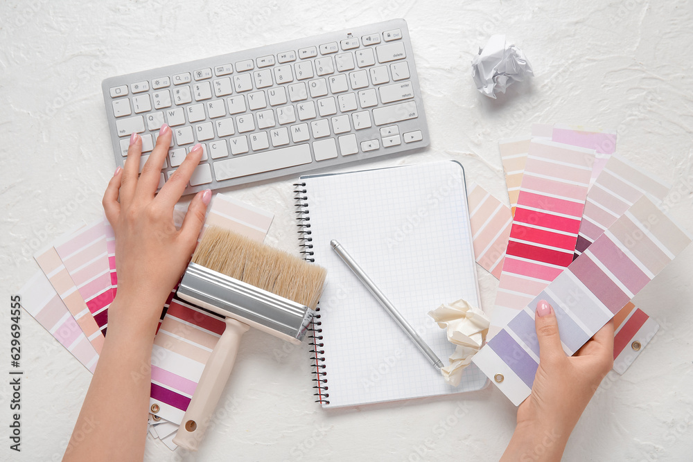 Female hands, color palettes, PC keyboard, notebook and brush on light background