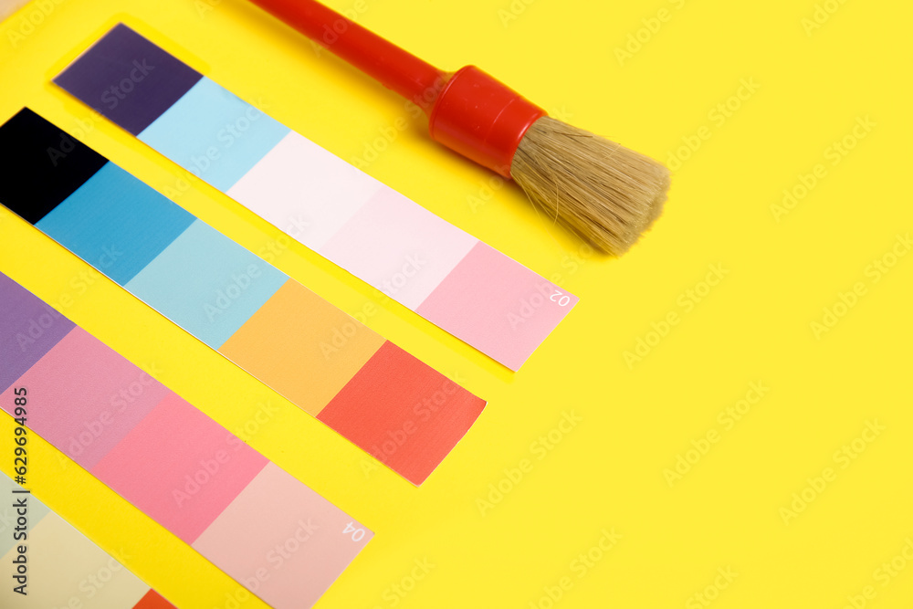 Many color palettes and brush on yellow background, closeup