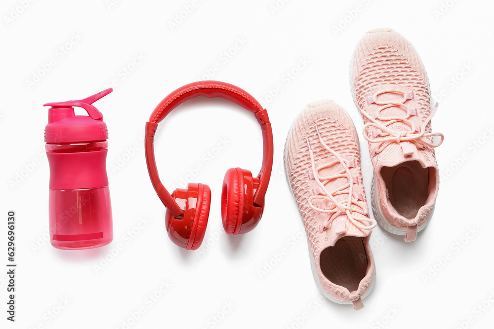 Bottle of water, sneakers and headphones on white background