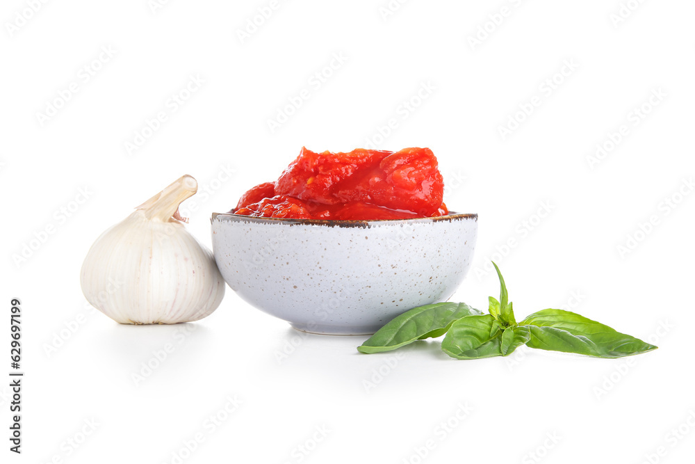 Bowl of canned tomatoes, basil and garlic on white background