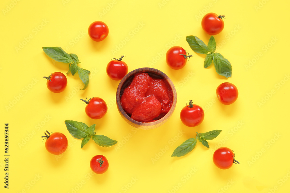 Composition with basil, canned and fresh tomatoes on yellow background