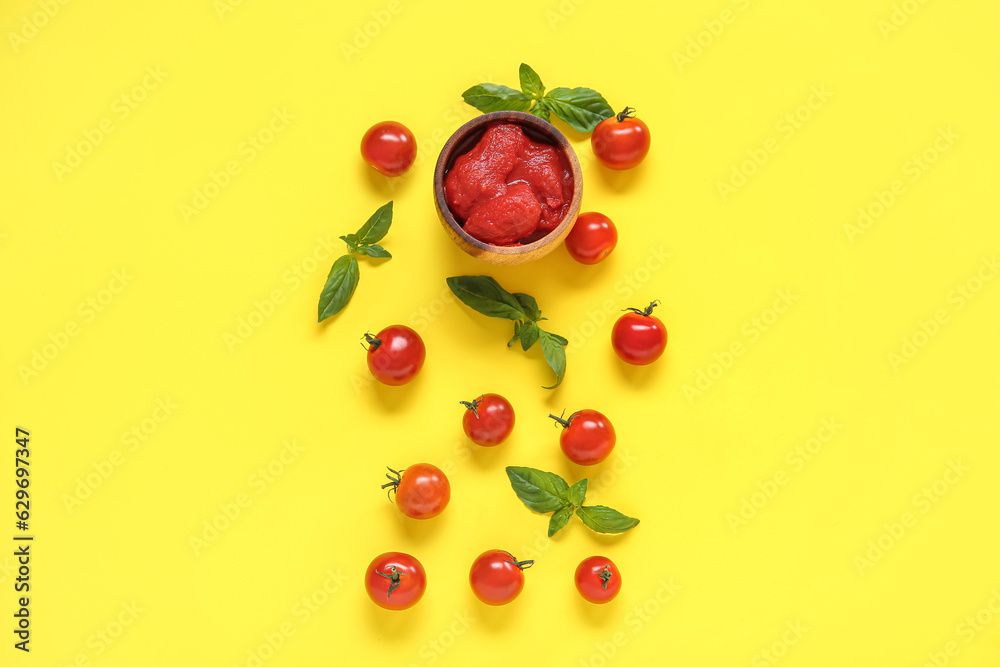 Composition with basil, canned and fresh tomatoes on yellow background