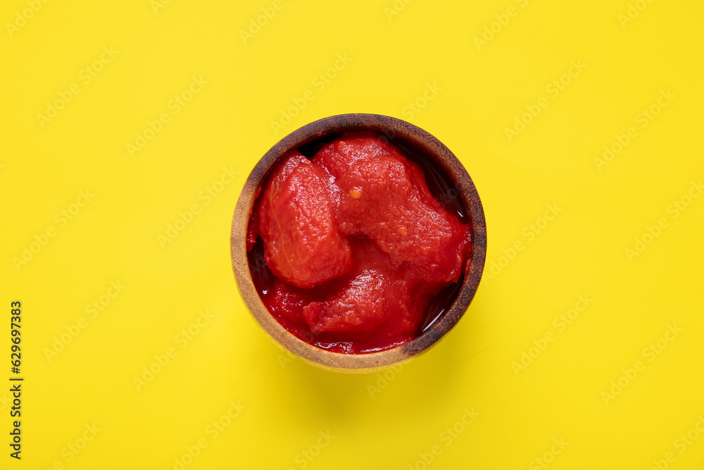 Bowl of canned tomatoes on yellow background