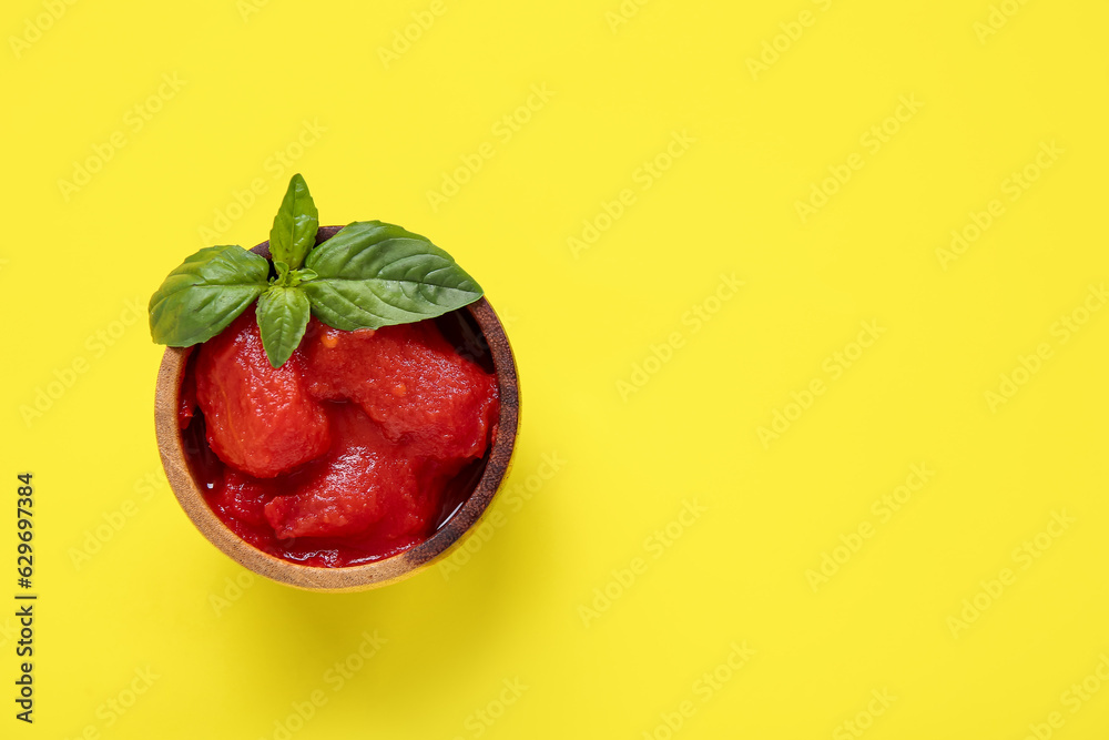 Bowl of canned tomatoes on yellow background