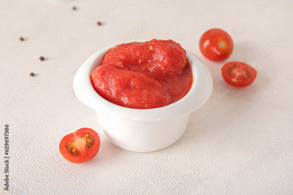 Bowl of canned tomatoes on light background