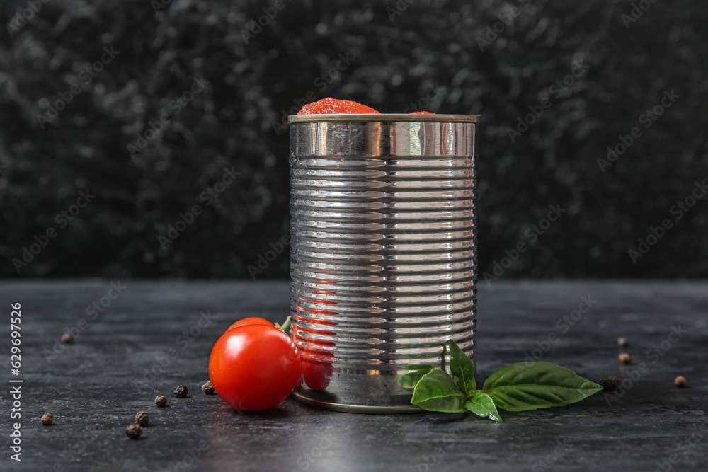 Tin can with tomatoes on dark background