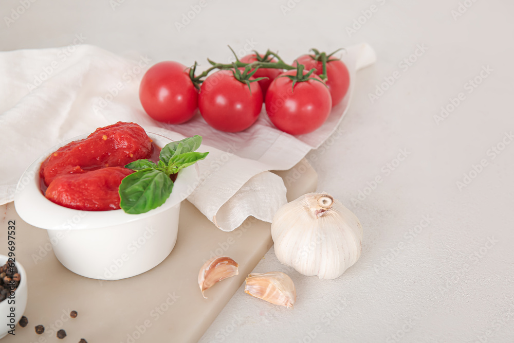 Bowl of canned tomatoes and spices on light background