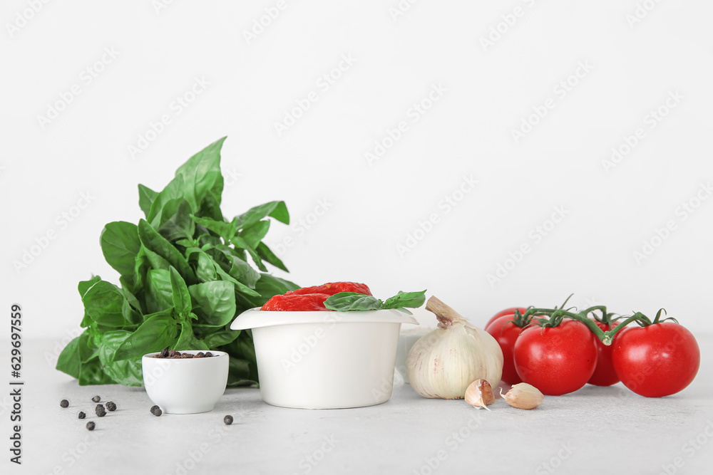 Bowl of canned tomatoes and spices on light background