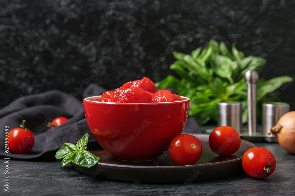 Bowl of canned and fresh tomatoes on dark background