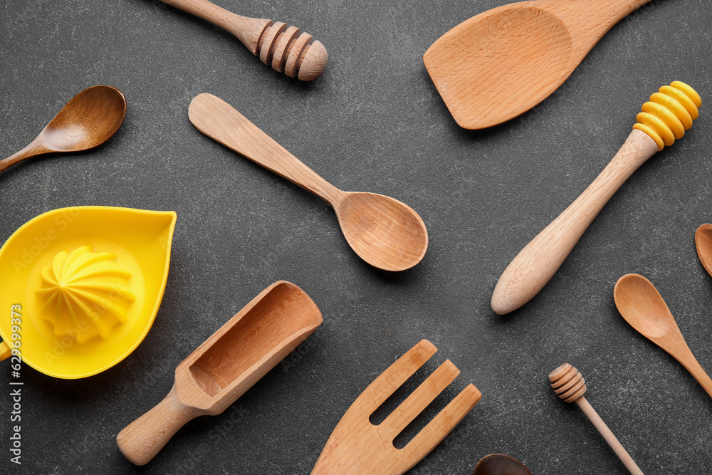 Set of different kitchen utensils with citrus juicer on dark background