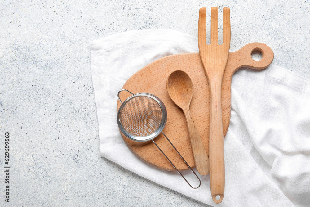 Set of kitchen utensils with napkin on light background