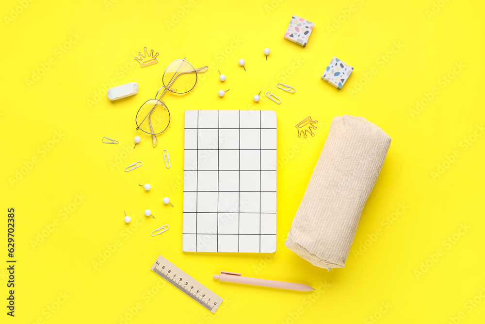 Composition with different stationery and eyeglasses on yellow background