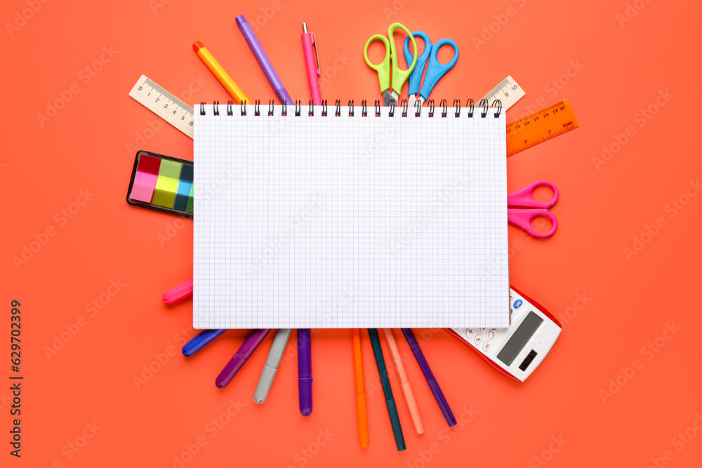 Composition with blank notebook and different stationery on color background