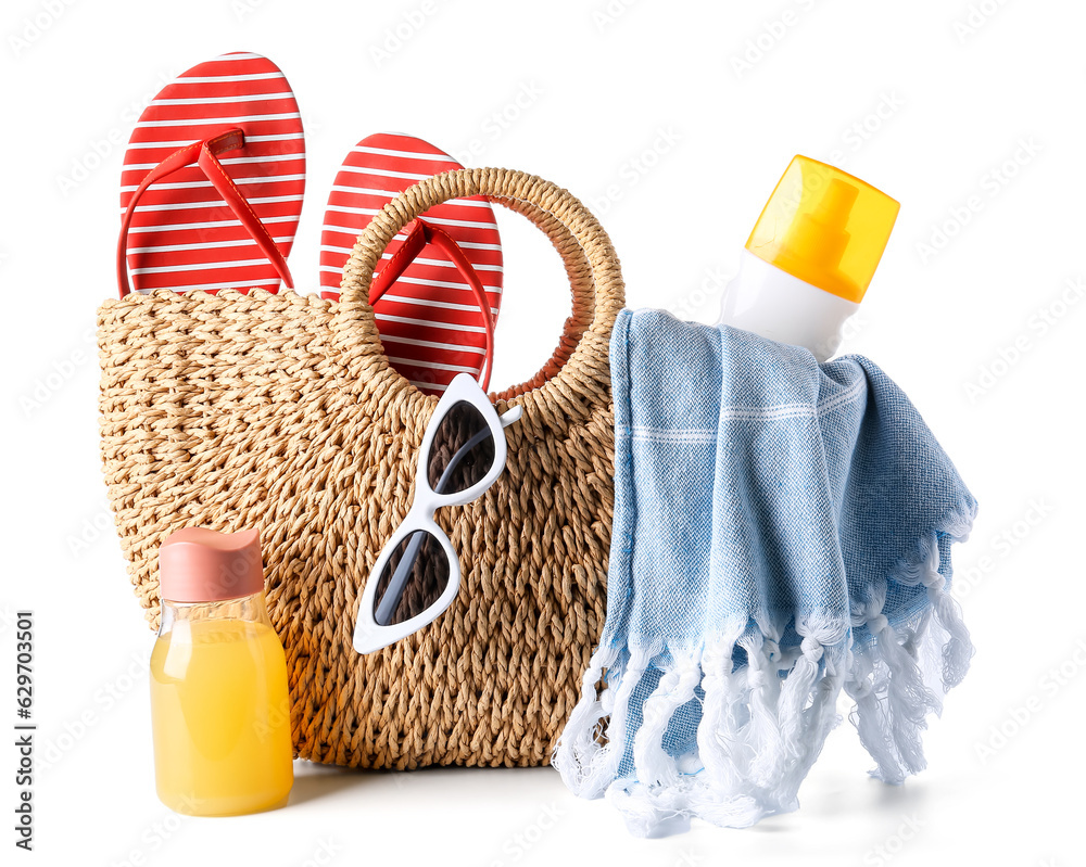 Female bag with beach accessories, bottle of juice and sunscreen cream on white background