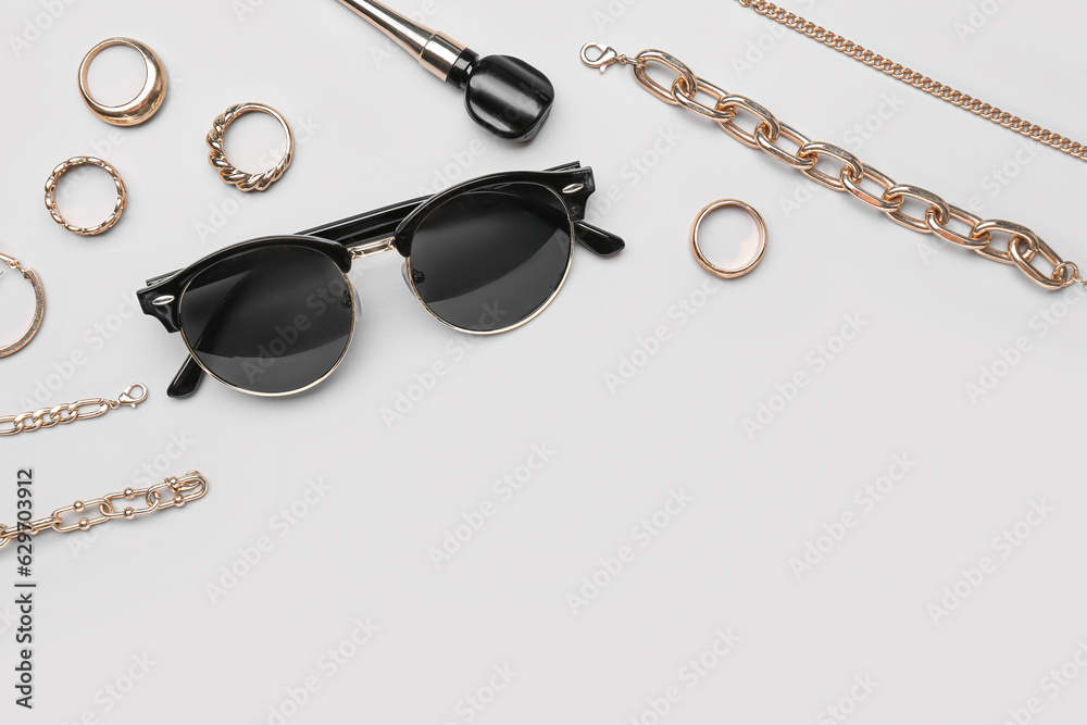 Stylish sunglasses with beautiful jewellery on grey background