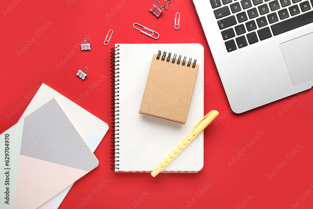 Composition with different stationery and laptop on red background