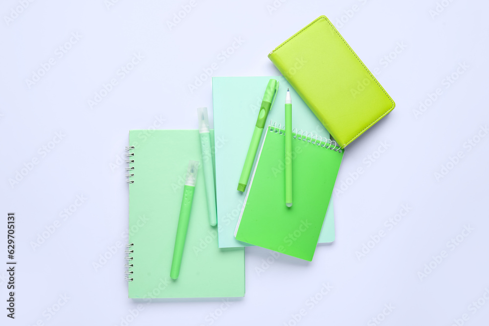 Composition with different notebooks, pens and markers on white background